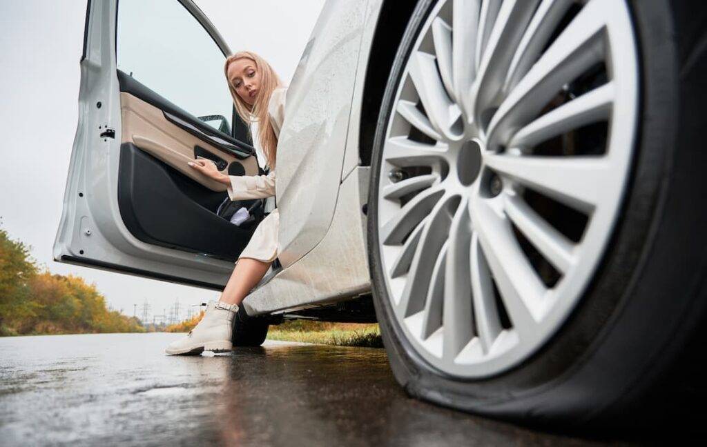 woman looking at punctured tyre